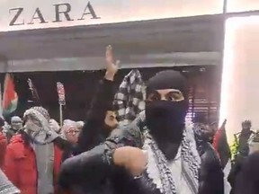 A masked Pro-Palestine protester threatens a passerby
