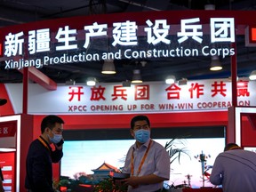 Staff members stand at a booth for the Xinjiang Production and Construction Corps.
