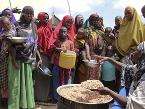FILE - Newly arrived Somalis, displaced by a drought, receive food distributions at makeshift camps in the Tabelaha area on the outskirts of Mogadishu, Somalia on March 30, 2017. The United Nations says at least three of every four Africans can't afford a healthy diet because of an "unprecedented food crisis." A U.N. report released Thursday, Dec. 7, 2023 with the African Union Commission says rising hunger and malnutrition in the continent of 1.4 billion people is caused by conflicts, climate change and the aftereffects of the pandemic.