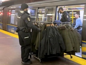 Police remove a rolling rack of coats from a SkyTrain car.