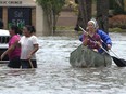 Residents paddle and walk along a flooded road Thursday, April 13, 2023, in Fort Lauderdale, Fla.