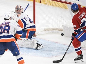 New York Islanders goaltender Semyon Varlamov is scored on by Montreal Canadiens' Joel Armia (not shown) as Canadiens' Christian Dvorak (28) and Islanders' Alexander Romanov (28) watch the puck during second period NHL hockey action in Montreal, Saturday, Dec. 16, 2023.
