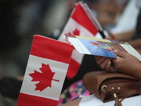 People hold Canadian flags at an immigration ceremony in Toronto.