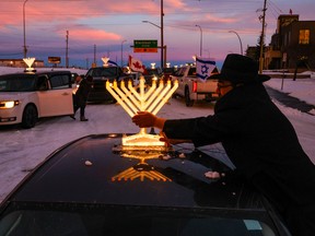 Daniel Shimonov cleans a menorah on top of his car before taking part in the Chabad Car Menorah Parade starting from Chabad Lubavitch of Alberta in Calgary last weekend.