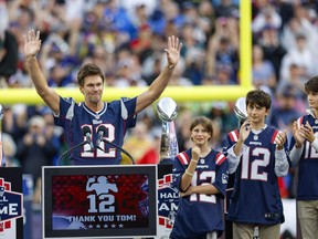 Former New England Patriots quarterback Tom Brady raises his arms after speaking while standing next to his daughter Vivian and sons Benjamin and Jack during the halftime ceremony of an NFL football game against the Philadelphia Eagles, Sunday, Sept. 10, 2023, in Foxborough, Mass.