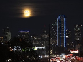 A Southwest Airlines plane makes its final approach at Dallas Love Field Airport near a the full moon and downtown Dallas buildings, Monday, Nov. 27, 2023. More Americans are expected to fly or drive far from home over Christmas than did last year, putting a cap on a busy year for travel.