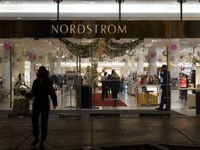 File - A security guard, right, stands at the entrance to a Nordstrom department store in Los Angeles, Dec. 2, 2021, where a smash-and-grab robbery took place. The National Retail Federation, the nation's largest retail trade group, has revised a report released in April that pulls back the claim that organized retail crime accounts for nearly half of overall industry shrink, which measures overall loss in inventory, including theft.
