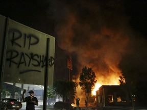 FILE- In this June 13, 2020 file photo, "RIP Rayshard" is spray-painted on a sign as flames engulf a Wendy's restaurant where Rayshard Brooks was shot and killed by police in Atlanta. Two of three people charged with arson in the burning of the restaurant have pleaded guilty after reaching deals with prosecutors.