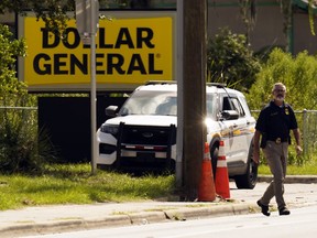 FILE - Law enforcement officials continue their investigation at a Dollar General Store that was the scene of a mass shooting, Aug. 27, 2023, in Jacksonville, Fla. Family members of three Black people who were fatally shot this summer inside the Dollar General store by a shooter who had posted racist writings sued the store's owner, operator and security contractor on Monday, Dec. 4, for negligence, claiming lax security led to their loved ones' deaths.