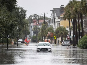 A car drives through a flooded street near the Battery, Sunday, Dec. 17, 2023, in Charleston, S.C.