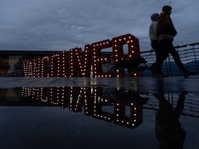 Heavy rains and strong winds in parts of B.C. throughout Christmas evening left thousands of customers without power on Boxing Day.&ampnbsp;People walk past a festive Vancouver sign on a rainy Christmas Day in Vancouver, B.C., Monday, Dec. 25, 2023.