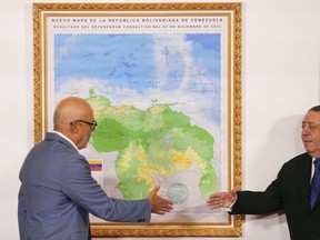 National Assembly President Jorge Rodriguez, left, and Chairman of the Special Commission for the Defense of Guyana Essequibo Hermann Escarra, shake hands after unveiling Venezuela's new map that includes the Essequibo territory, a swath of land that is administered and controlled by Guyana but claimed by Venezuela, in Caracas, Venezuela, Friday, Dec. 8, 2023.