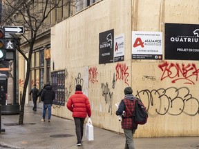 Shoppers walk past a boarded up storefront on Ste-Catherine St. in downtown Montreal, Tuesday, Dec. 19, 2023.