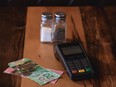 Payment terminal on table next to Canadian money