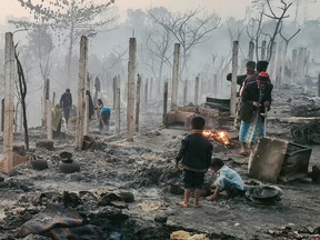 Rohingya refugees look through the debris