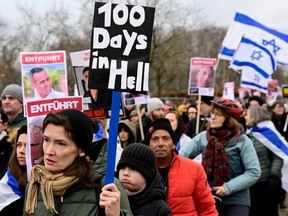 Demonstrators carry Israeli flags and placards with the portraits of Israeli hostages during a march to mark the 100th day of the Israeli hostages' captivity during the ongoing Israeli-Palestinian conflict, on Jan. 14, 2024 in Berlin.