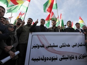 Protesters hold a banner and Kurdish flag