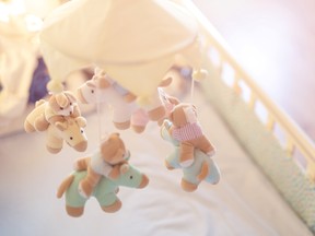 Close-up baby crib with musical animal mobile at nursery room