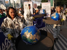 Activists dressed to represent the oil and gas industry pretend to heat the globe in giant frying pans during the COP28 climate conference in Dubai on Dec. 9, 2023.