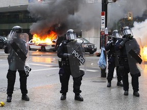 Toronto police on the street amid burning cars during the G20 Summit in 2010.