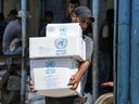 Un hombre palestino carga cajas de alimentos fuera de un centro de distribución de ayuda gestionado por la Agencia de Obras Públicas y Socorro de las Naciones Unidas (UNRWA) en el campo de refugiados de Bureij, en la Franja de Gaza, en julio de 2019.