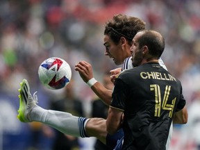 Vancouver Whitecaps' Simon Becher, back, kicks the ball as he vies for it against Los Angeles FC's Giorgio Chiellini during the second half of an MLS soccer match, in Vancouver, B.C., Saturday, Oct. 21, 2023. The Whitecaps have transferred Becher to Danish side AC Horsens, the Major League Soccer club announced Wednesday.