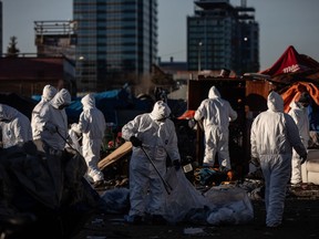 Cleanup crews tear down homeless encampments in Edmonton on Friday, Dec. 29, 2023.&ampnbsp;A man has been discovered dead at a homeless encampment north of Edmonton's downtown, prompting city officials to briefly pause their plans to clear the camp.
