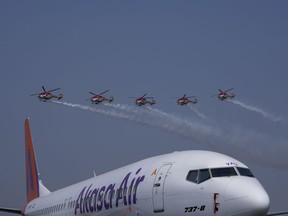 Akasa Air's 737-8 aircraft is seen in foreground as Indian Air Force Sarang helicopters perform an aerobatic display during the 'Wings India 2024,' a biennial aviation event at Begumpet airport in Hyderabad, India, Thursday, Jan. 18, 2024.