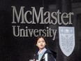 A pedestrian walks past McMaster University signage on Toronto's Bloor Street West