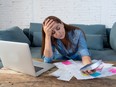 Portrait of worried young single mother feeling stressed while working through finances