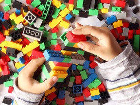 Close up of child's hand playing plastic toy building blocks, top view from above.