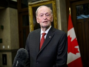 Jean Chretien speaks next to a Canadian flag.