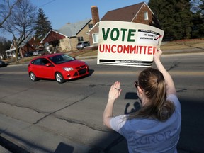 A woman holds up a "Vote Uncommitted" sign."
