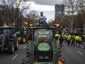 A farmer sits atop a tractor during a protest outside the European Parliament offices in Madrid, Spain, Monday, Feb. 26, 2024.