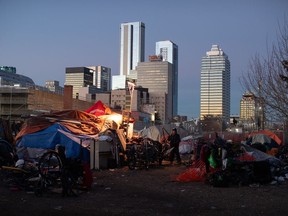 A man prepares to move his belongings as police and cleanup crews prepare to tear down homeless encampments in Edmonton on Friday, Dec. 29, 2023.