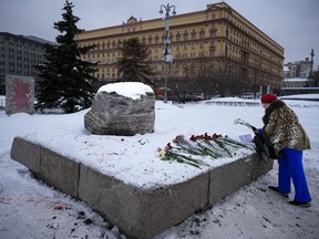 A woman lays flowers to pay tribute to Alexei Navalny at a monument in Moscow
