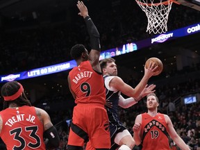 Dallas Mavericks' Luka Doncic goes to the basket against Toronto Raptors' RJ Barrett during second half NBA basketball action in Toronto on Wednesday, February 28, 2024.