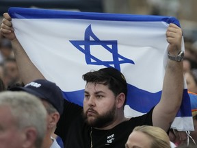 A man holds up an Israeli flag as he attends a rally in support of Israel
