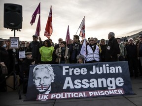 Demonstrators pose for a photo behind a banner reading "Free Julian Assange"