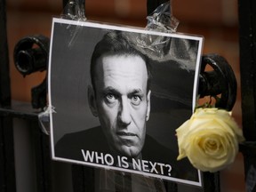 A flower and a picture are left as a tribute to Russian politician Alexi Navalny, near to the Russian Embassy in London, Sunday, Feb. 18, 2024.