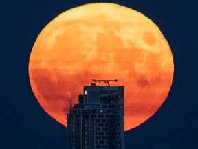 A full moon rises above a Vancouver skyscraper.