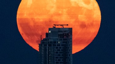 A full moon rises above a Vancouver skyscraper.