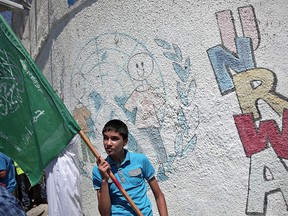 A Palestinian boy holds up a Hamas flag as he rallies for funding for the U.N. Relief and Works Agency (UNRWA)
