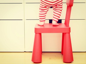 Little girl climbing on baby chair.
