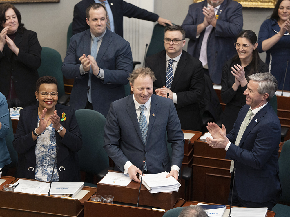 Finance and Treasury Board Minister Allan MacMaster, bottom centre, is applauded by party members while tabling the provincial budget at the Nova Scotia legislature in Halifax.