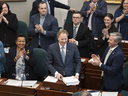 Finance and Treasury Board Minister Allan MacMaster, bottom centre, is applauded by party members while tabling the provincial budget at the Nova Scotia legislature in Halifax.