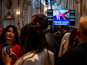 People socialize around a TV showing Donald Trump picture.