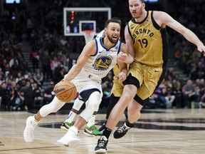 Golden State Warriors guard Stephen Curry (30) drives past Toronto Raptors centre Jakob Poeltl (19) during first half NBA basketball action in Toronto on Friday, March 1, 2024.