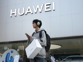 FILE - A customer carries his purchased Huawei product outside a Huawei store after he attended the Huawei new product launch conference in Beijing, on Sept. 25, 2023. Chinese telecoms gear company Huawei Technologies has reported its profit more than doubled last year as its cloud and digital businesses thrived in spite of U.S. sanctions.
