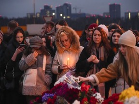 People lay flowers and light candles standing next to the Crocus City Hall, on outskirts of Moscow on Saturday, March 23, 2024. The death toll from the attack has climbed to 133.